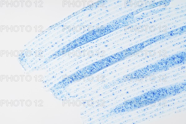 A close-up of face scrub smears showcases fine blue micro-exfoliating particles against a smooth
