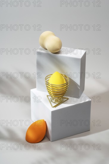 Vibrant cosmetic sponges in orange and yellow, elegantly arranged on minimalist white platforms