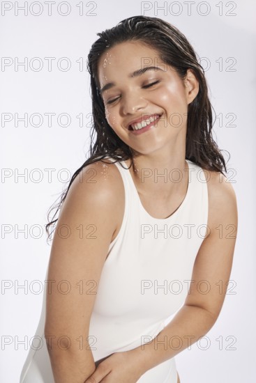 Fresh model portrait of a delighted woman, with eyes closed with a subtle smile, styled in a white