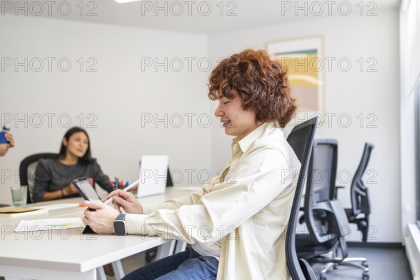 A team of coworkers collaborating in a bright, modern office One person is focused on a tablet,