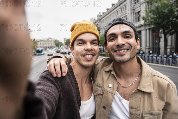 A Colombian gay couple smiling while taking a selfie outdoors, capturing an authentic, joyful