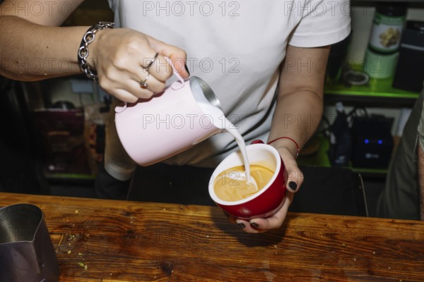 A barista skillfully pours milk into espresso to create latte art, highlighting the process of