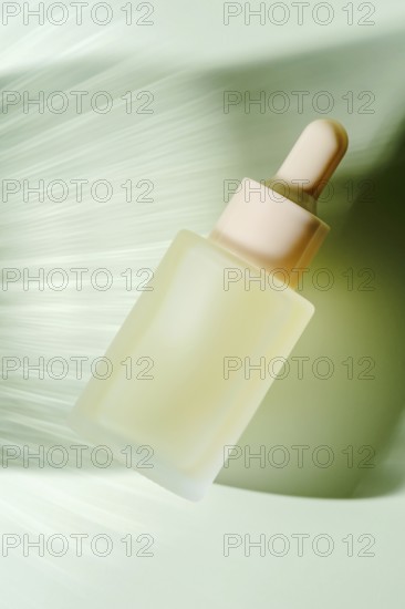 A frosted glass serum dropper bottle hovers against a blurred green background, depicting motion