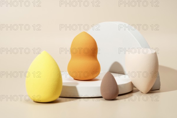 A variety of colorful cosmetic sponges in different shapes and sizes on a light background,