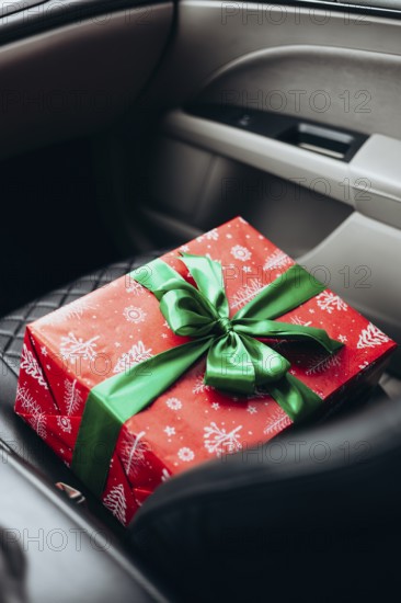 A beautifully wrapped red gift with a green ribbon rests on a car seat, capturing the anticipation