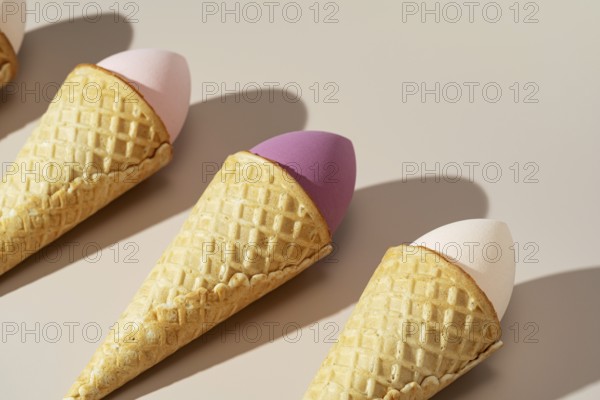 Innovative arrangement of colorful cosmetic sponges nestled in waffle cones, set against a soft,