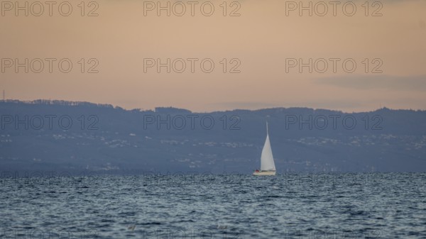A serene scene of a sailboat gracefully moving across a calm lake in Geneva, set against a backdrop