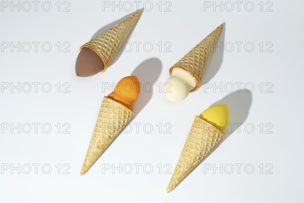 Four colorful cosmetic sponges creatively arranged in waffle cones, resembling ice cream scoops,