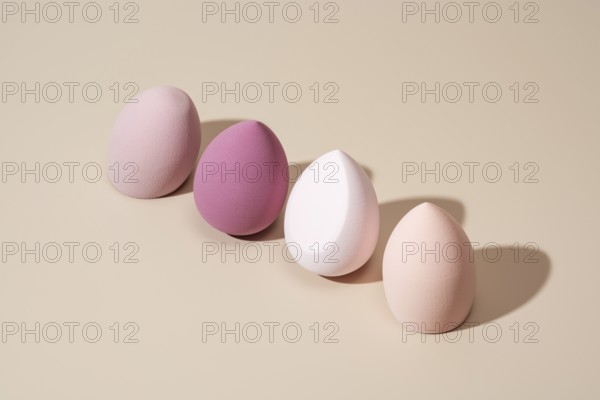 A row of pastel cosmetic sponges in various soft tones on a neutral backdrop, showcasing their