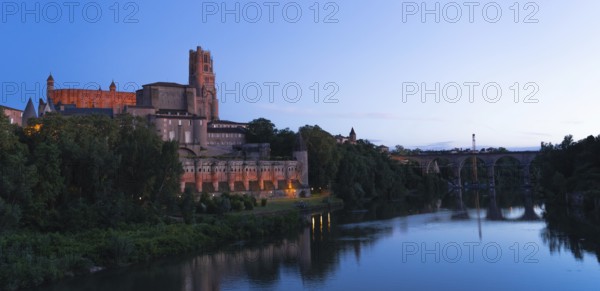 A stunning view of historic Berbie Palace en Albi, with serene waters reflecting the evening sky