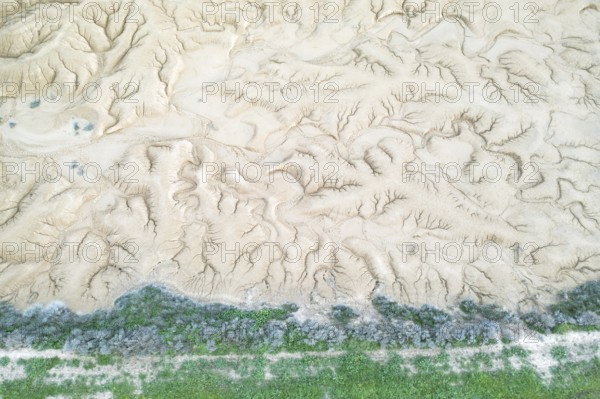 Aerial view of a uniquely textured, arid landscape showcasing patterns of erosion A strip of green