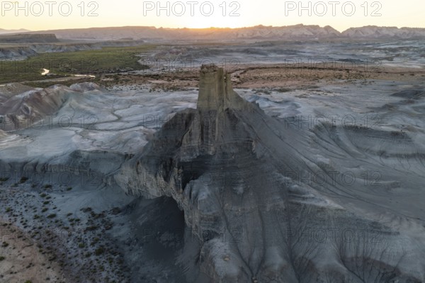 A sweeping aerial view captures the vast, eroded terrain of Utah's desert at sunset, highlighting