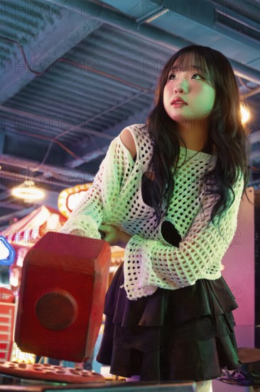 Asian Gen Z girl immersed in arcade fun, surrounded by vibrant lights and playful atmosphere Her