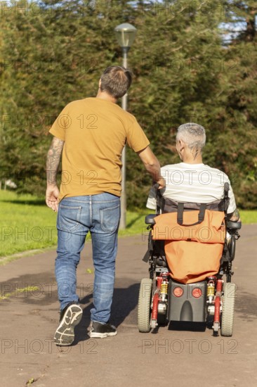 A thoughtful moment capturing a person walking with a friend in a wheelchair with a cerebral palsy