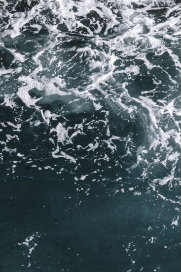 Moving seawater with white foam and dynamic texture. Waves and bubbles create a natural and