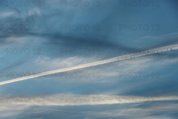 Airplane contrail across a clear blue sky. The white streak contrasts beautifully with the soft