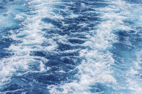 Turbulent sea waves with foam and ripples in deep blue water. The movement captures the raw power