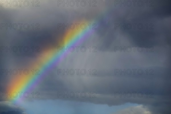 A stunning photograph capturing a vivid rainbow arching over a dark, stormy sky, showcasing the