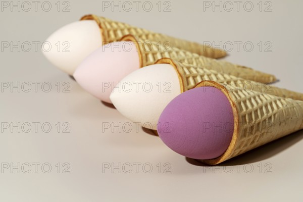 Four colorful cosmetic sponges creatively placed in ice cream cones The sponges, in pastel shades,
