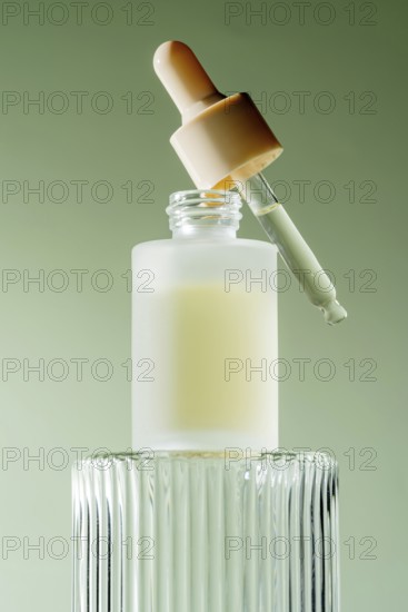 An elegant serum dropper bottle with a pipette resting on its rim, filled with a milky serum, set