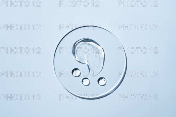 Transparent liquid droplets rest on a smooth, light surface The image showcases the purity and