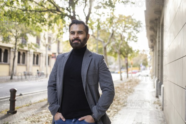 An Indian man, dressed as a businessman in winter attire, strolls along a city street with his