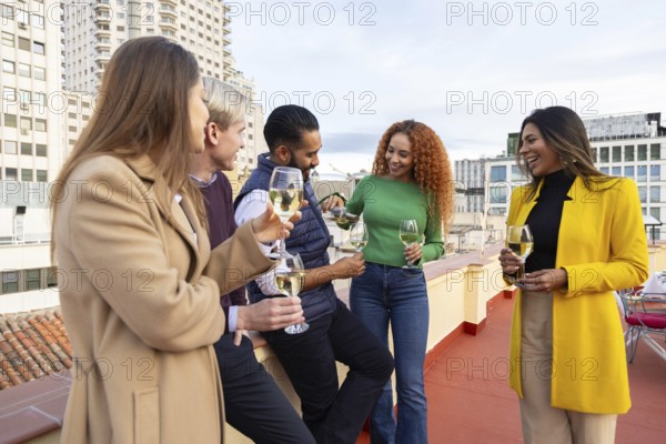 A diverse group of friends celebrates with drinks at a rooftop party in the city They are laughing
