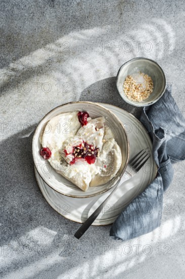 Boiled Ukrainian varenyky filled with cherry, served with a topping of sour cream and chopped nuts