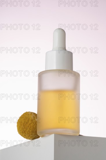 Elegantly displayed cosmetic serum bottle with a dropper, positioned on a geometric podium against
