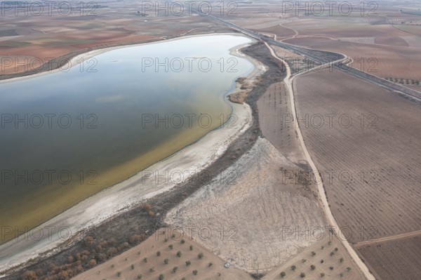Aerial view of Toledo Lagoons, Spain, showcasing a serene lake amidst farmland. Home to diverse