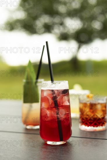 A bright assortment of refreshing cocktails multicolored on a table The focus is on a red drink