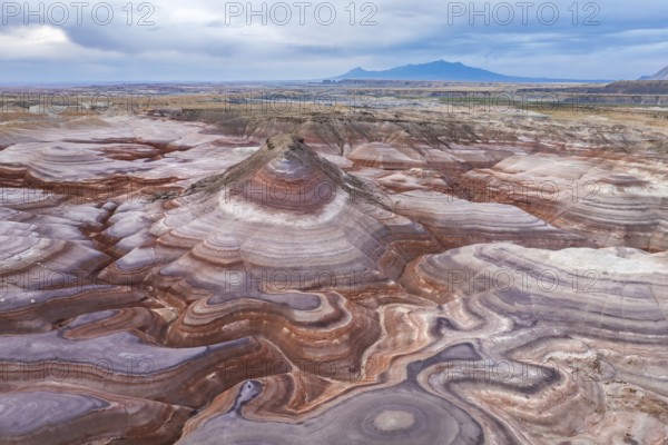 A captivating drone image of an unrecognizable person standing on the unique, multicolored rock