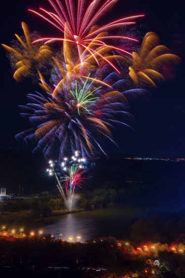 Vibrant fireworks illuminate the night sky above the Ebro River, casting colorful reflections on