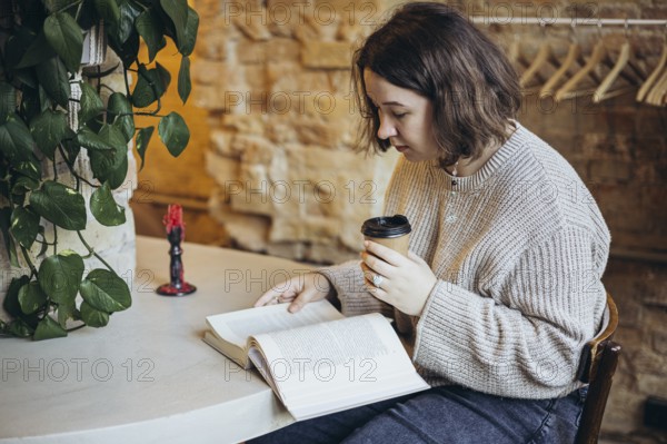 A young woman enjoys reading a book in a cozy bookstore setting She is sipping coffee, surrounded
