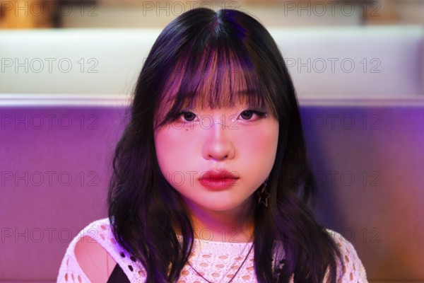 An Asian Gen Z girl is immersed in the vibrant atmosphere of an arcade Her expression reflects the