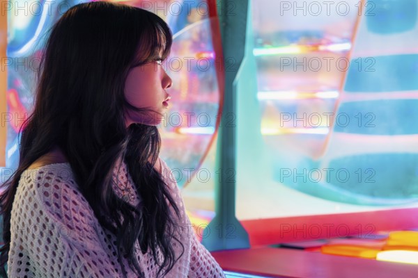 A young Asian Gen Z girl enjoys vivid lights and colors in an arcade, capturing the essence of