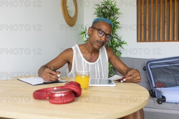 LGBTQIA+ person meticulously preparing for the holidays, planning with a notebook and tablet. A