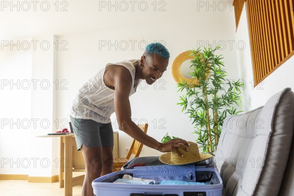 LGBTQIA+ man with teal hair packs a suitcase for a holiday, embodying joy and diversity. The bright