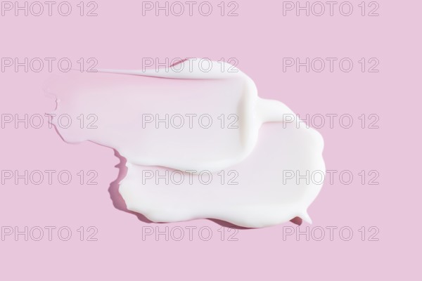 A delicate smear of creamy cosmetic product, displaying texture against a soothing pink background.
