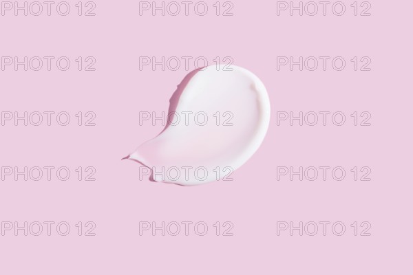 A high-quality image featuring a dollop of cosmetic cream smeared on a pastel pink background,