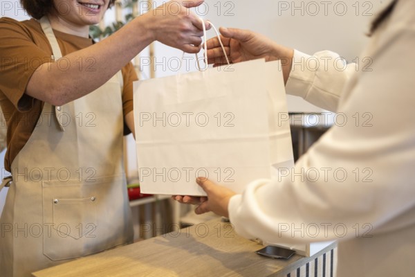 A friendly store employee hands a paper shopping bag to a customer The image captures a moment of