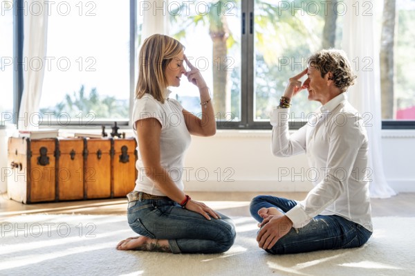 A man and woman meditate in a brightly lit room, utilizing alternative work strategies. The woman