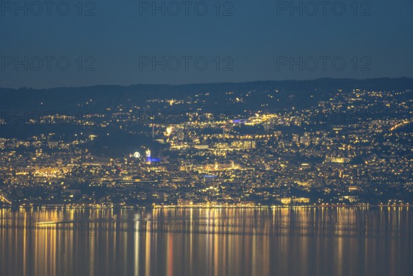 A captivating nighttime view of Lausanne, Switzerland, with the city lights reflecting on the calm