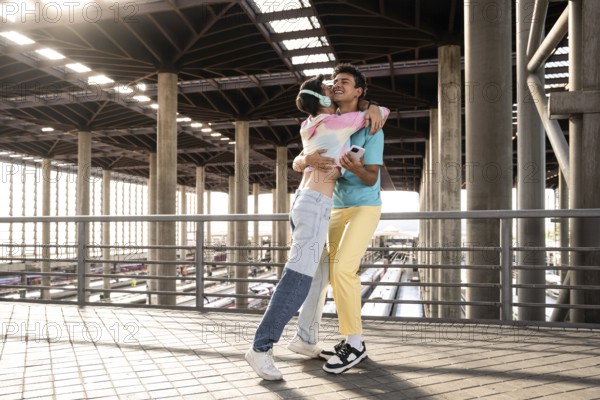 A joyful moment for a couple embracing each other at a train station. The sunlight filters through