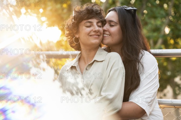 A loving lesbian couple shares a tender embrace outdoors, surrounded by vibrant nature. The