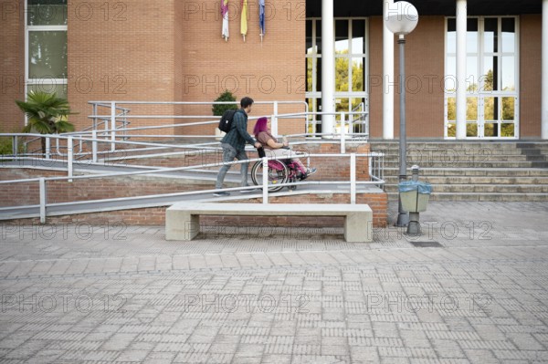A college couple navigates a ramp on campus, highlighting accessibility The woman, in a wheelchair