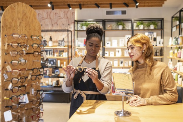 A retail employee helps a customer choose eyeglasses in a stylish boutique. The modern store is