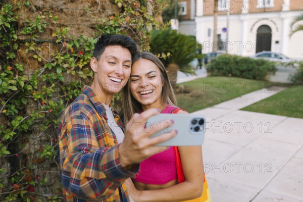 A joyful lesbian couple takes a selfie while enjoying a sunny day in a park. Their smiles reflect