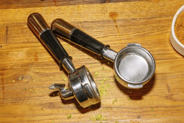 Two espresso machine portafilters rest on a wooden counter, displaying their metal baskets and