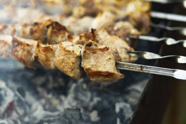 Close-up of juicy, chunky kebabs sizzling on skewers over a smoky grill at a bustling street fair,